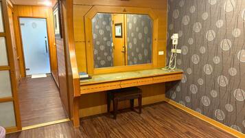 A compact room with a wooden desk, a mirror, and a telephone.