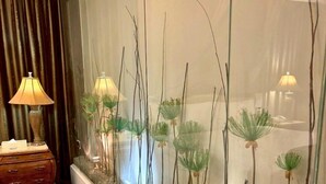 A room with a long glass aquarium filled with plants and pebbles, a wooden dresser, and a lamp. - Langkei Hotel (Taoyuan City)
