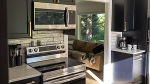 A modern kitchen with dark cabinets, stainless steel appliances, and a view of the outdoors. - Iron Sunset-Summer Fun at Iron Sunset – Lake Access & Pet-Friendly! (Iron River)