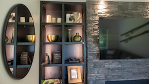 A modern interior with a stone wall and a wooden shelf unit displaying various decorative items. - Iron Sunset-Summer Fun at Iron Sunset – Lake Access & Pet-Friendly! (Iron River)