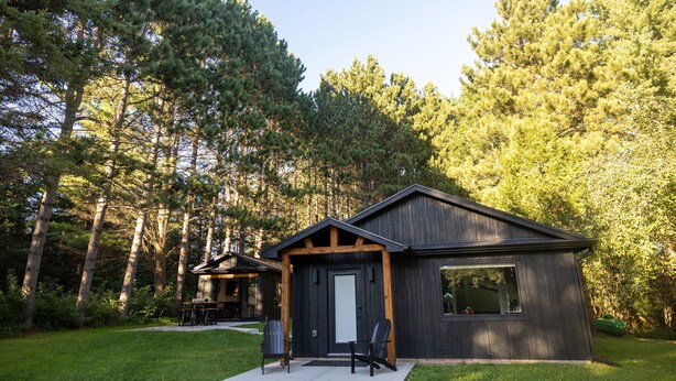A cabin with a dark exterior, a front door, and a window. There is a lawn in front of the cabin. - Iron Sunset-Summer Fun at Iron Sunset – Lake Access & Pet-Friendly! (Iron River)