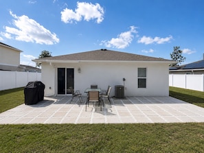 Une terrasse avec une table et des chaises, un barbecue et un appareil de climatisation.