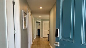 Un pasillo con suelo de madera, puertas blancas y una puerta verde azulada.