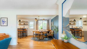 Een ruime eethoek met een ronde tafel en stoelen, een bank en een houten bankje.