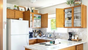 A kitchen with wooden cabinets, a refrigerator, a sink, and a stove.