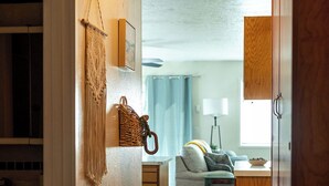 A hallway leading to a living room with a sofa, a lamp, and a kitchen area with wooden cabinets.