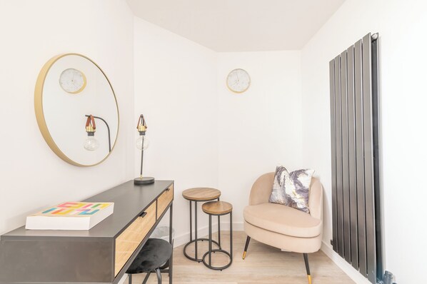 Una habitación moderna con escritorio, dos taburetes, una silla y un radiador.