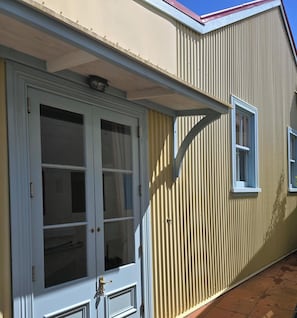 A building with a white door, a window, and a metal awning.