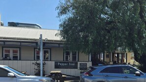 Ein Restaurant namens 'Pepper Tree' mit einer Schautafel, parkenden Autos und einem Baum im Hintergrund.