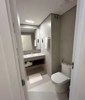 A modern bathroom with a toilet, sink, and mirror. - PYRENÉUS RESIDENCE (Pirenópolis)