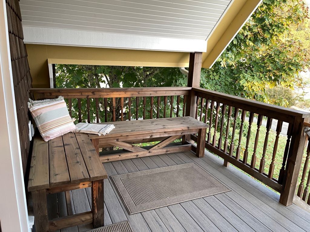 A wooden deck with a bench and a table, surrounded by a wooden railing.