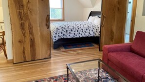 Un dormitorio con cama, sofá rojo y puerta corredera.