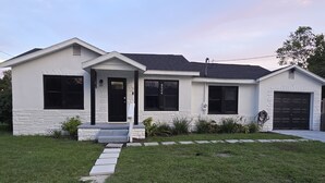 Ein eingeschossiges Haus mit Veranda, Garage und gepflegtem Rasen.