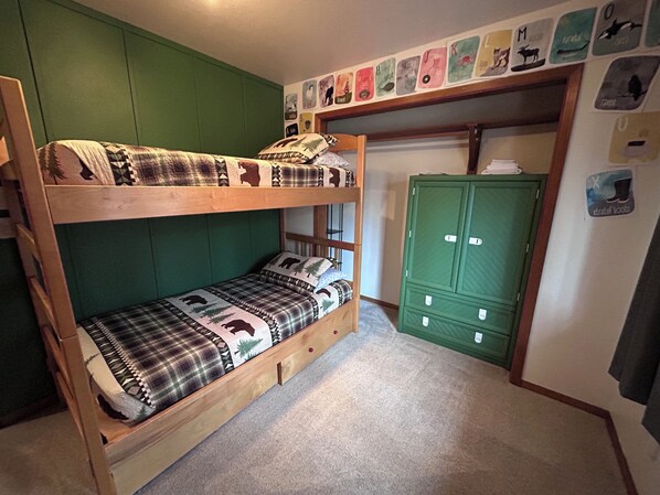 A bunk bed with a green wall and a green wardrobe.