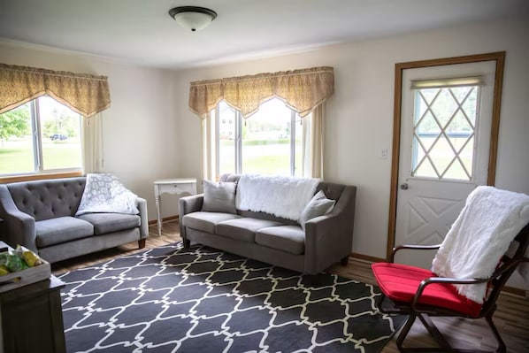 A living room with two grey sofas, a black and white patterned rug, and a red chair.