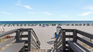 A beach with wooden walkways leading to the shore, umbrellas, and beach chairs.