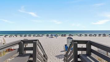 A beach with wooden walkways leading to the shore, umbrellas, and beach chairs.
