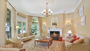 Ein traditionell eingerichtetes Wohnzimmer mit Kamin, zwei Sofas, einem Couchtisch und einem gemusterten Teppich.