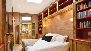 Ein Schlafzimmer mit einem großen Bett, Holzregalen, einem Spiegel und einem Oberlicht.