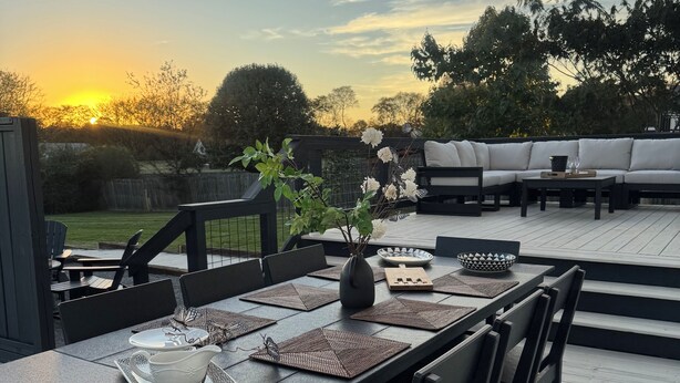 A deck with a dining table set for four, surrounded by chairs, and a sofa in the background. - Charming Villa mins to Leipers Fork, Historic Franklin, Southall Farm & Inn. (Franklin)