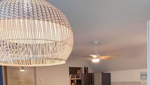A modern living room with a blue sofa, a wooden coffee table, and a large woven light fixture.