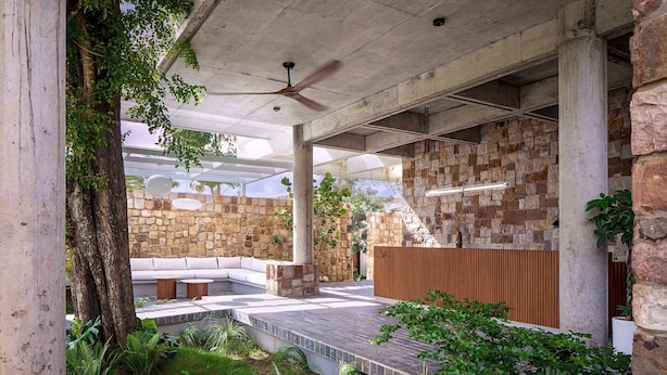 Un espace extérieur aménagé avec un patio, un mur en pierre, une terrasse en bois et un coin salon.