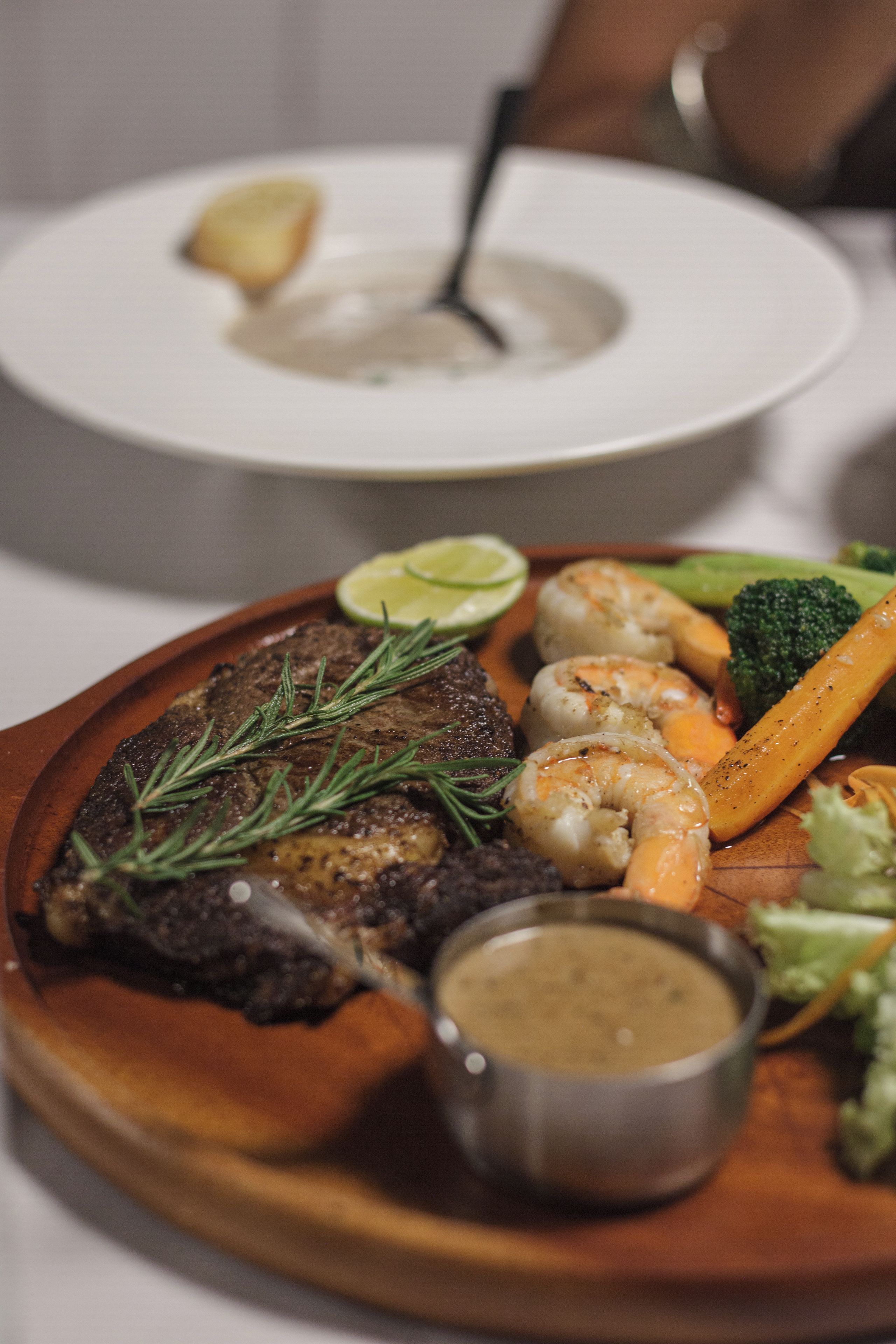 Une assiette de nourriture comprenant un steak, des crevettes et des légumes.