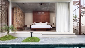 Une chambre moderne avec un grand lit, un mur en pierre et une vue sur une piscine.