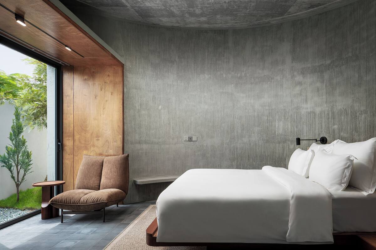 A modern bedroom with a large bed, a wooden chair, and a small table.