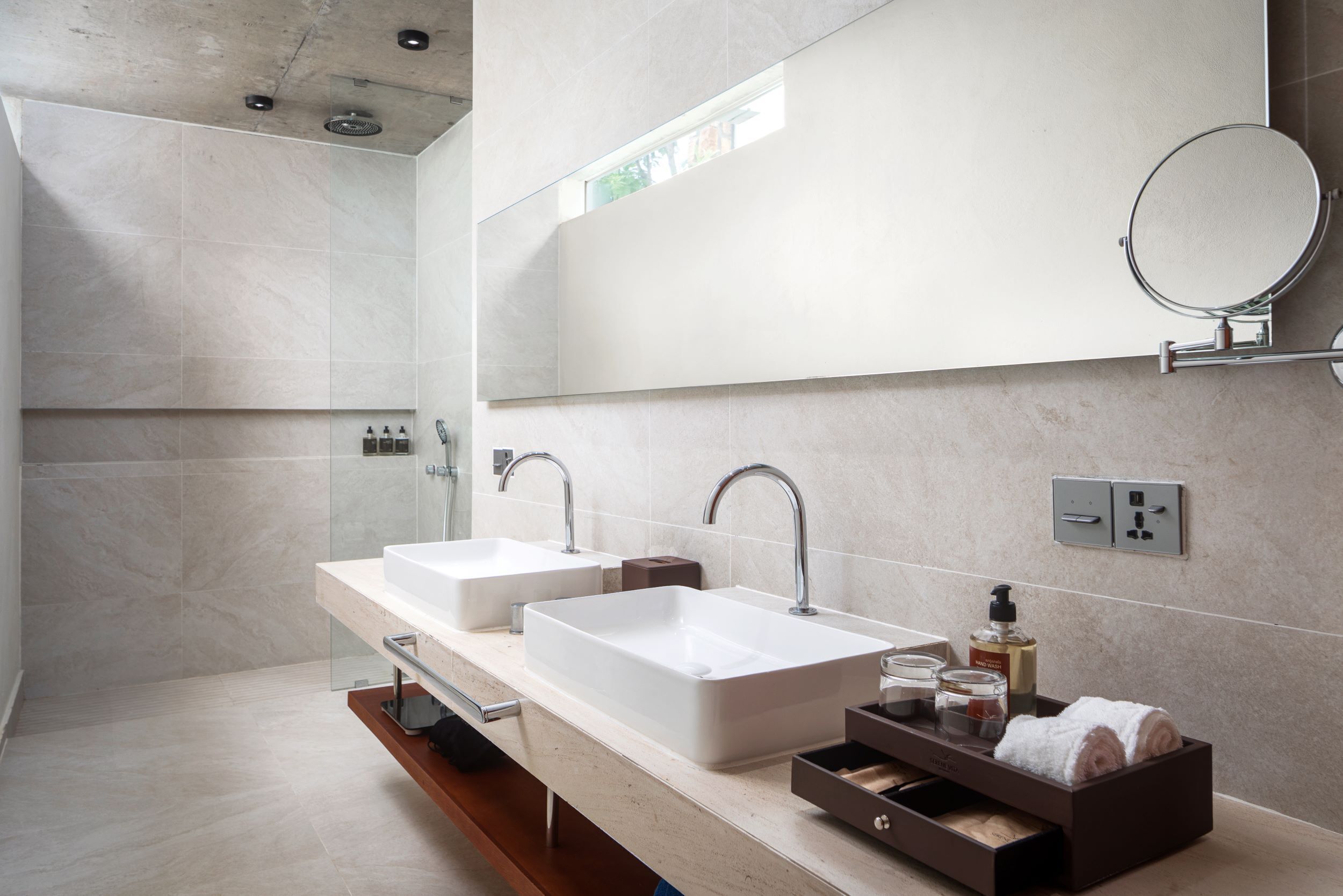A modern bathroom with two sinks, a mirror, and a shower.