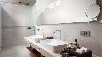 A modern bathroom with two sinks, a mirror, and a shower.