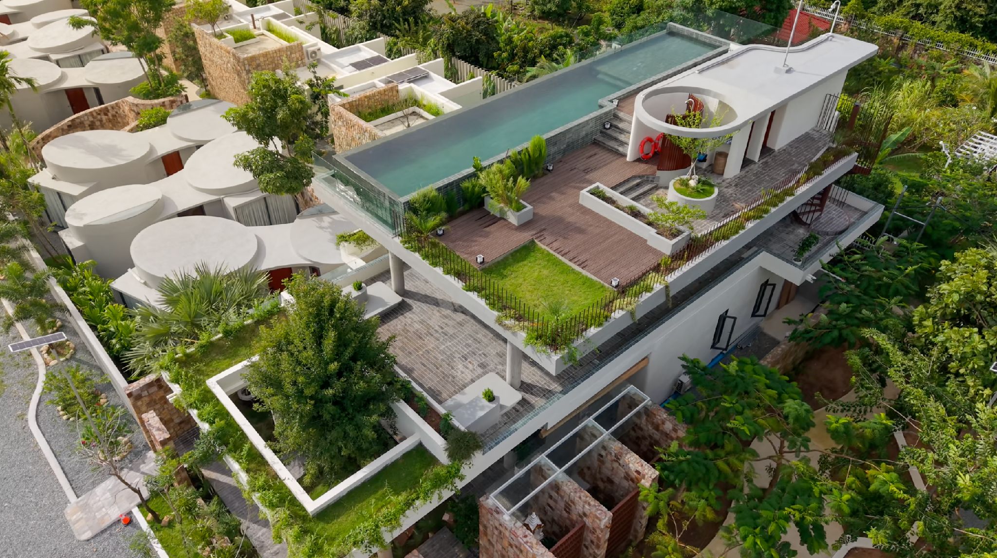 Un complesso residenziale moderno con piscina centrale, giardino pensile e numerosi balconi.