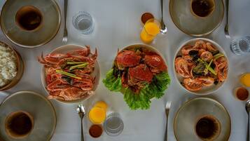 A dining table set with plates of seafood, bowls of rice, and glasses of orange juice.