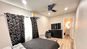 A bedroom with a bed, a dresser, a TV, and a ceiling fan. - Tranquil Beautiful Studio (Las Vegas)