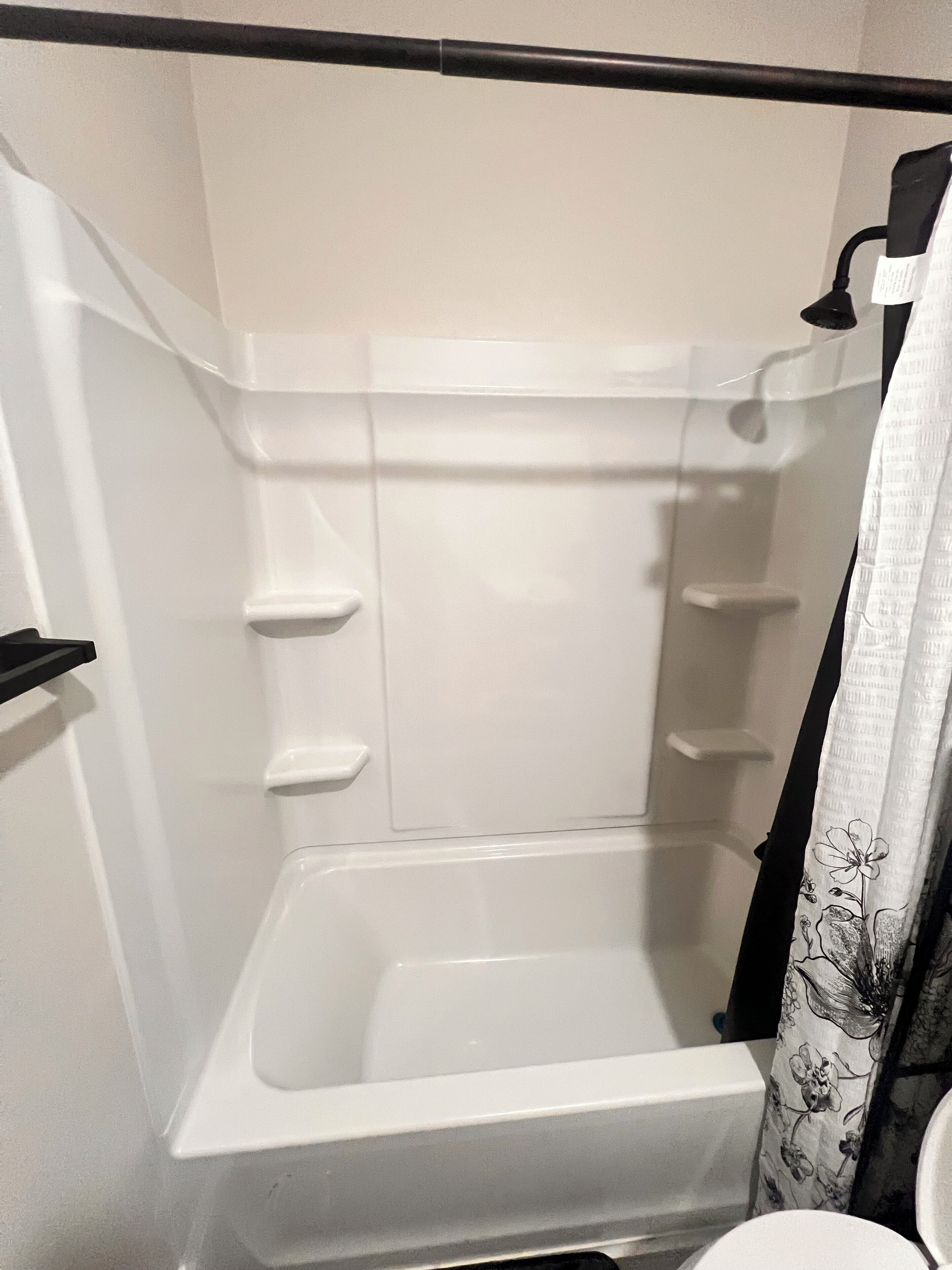 A white bathtub with a shower curtain and a black towel rack.