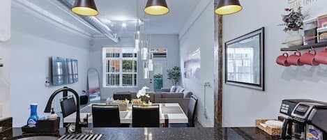Une cuisine moderne dotée d’un plan de travail en granit, d’une machine à café et de luminaires suspendus.