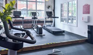 A fitness center with treadmills, a stationary bike, and a bench.