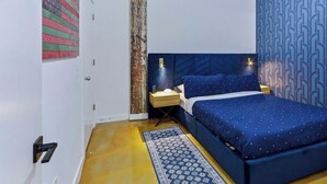 A bedroom with a bed, nightstands, a patterned rug, and a wall with a geometric design.