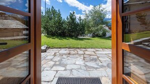 Un pati de pedra amb una zona enjardinada i arbres.