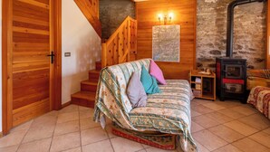 Una habitació acollidora amb una escala de fusta, un llit amb roba de llit estampada, un mapa a la paret i un foc de llenya.