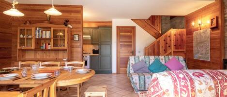 L’intérieur d’un chalet en bois chaleureux et accueillant, avec un coin repas, un canapé et une cuisine.