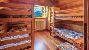 Una cabana de fusta amb lliteres, una finestra que dona a una vista de muntanya i un radiador.
