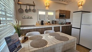 Cozinha moderna com ilha central, frigorífico branco e armários de madeira.