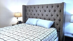A neatly made bed with a patterned bedspread, a tufted headboard, and two bedside lamps. - Paddleboards, Air Hockey, Grill, Fire Pit, W/D, Brkfst, Sleeps 20 (Page)