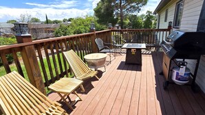 A wooden deck with a grill, chairs, and a table. - Paddleboards, Air Hockey, Grill, Fire Pit, W/D, Brkfst, Sleeps 20 (Page)