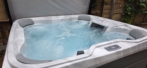 A hot tub with a control panel, surrounded by a wooden fence and foliage. - Hot Tub. Paddleboards, Air Hockey, Grill, Fire Pit, W/D, Sleeps 22 (Page)