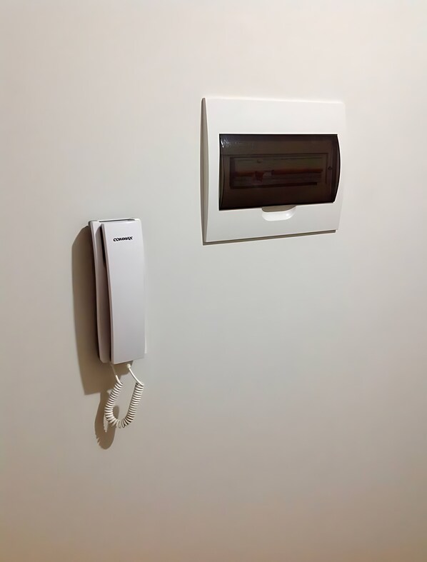 A white wall-mounted telephone and a white intercom system.