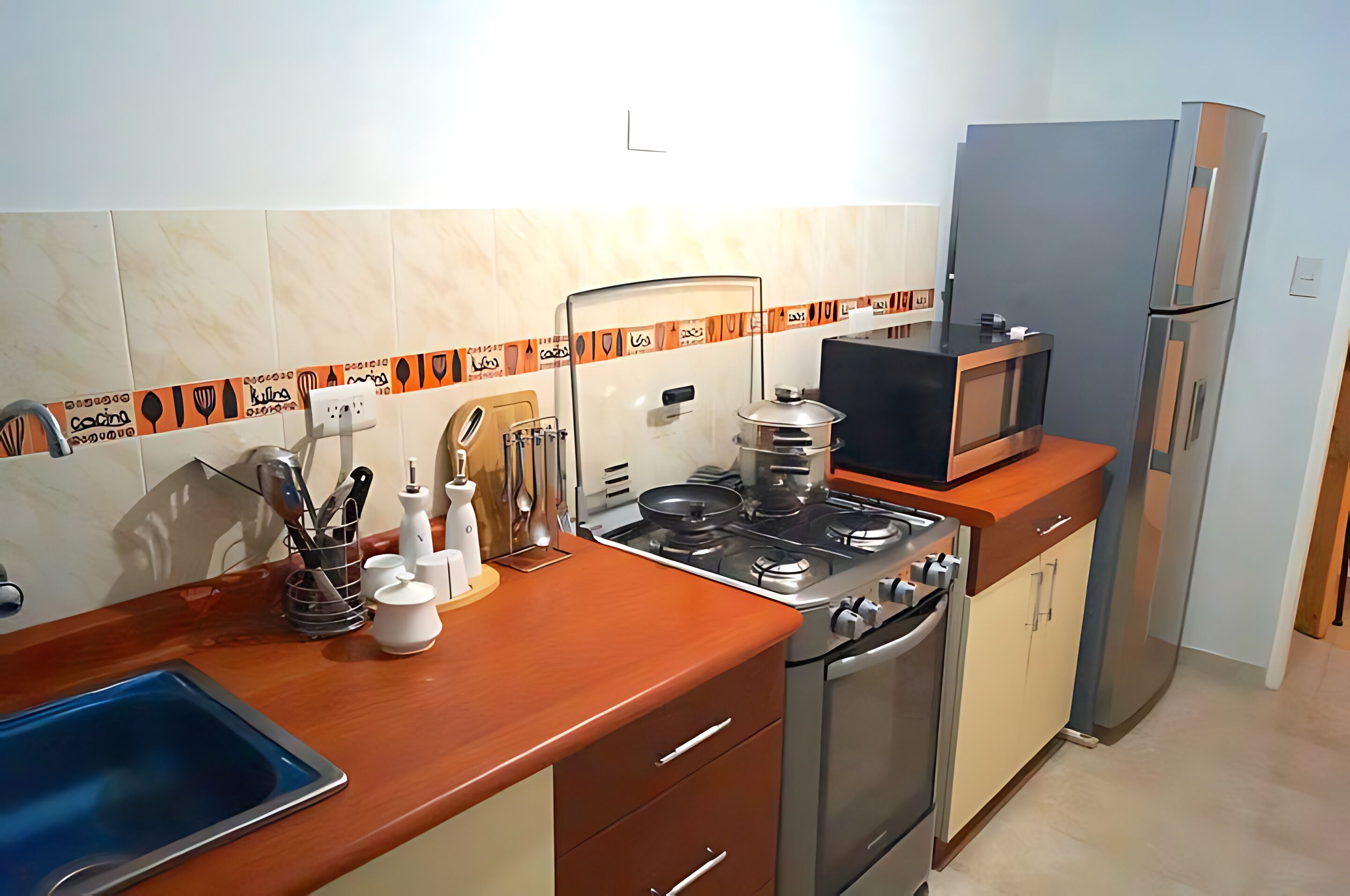 A kitchen with a sink, stove, microwave, and refrigerator.