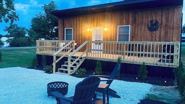 Une cabane en bois dotée d’une terrasse, de meubles de jardin et d’un escalier menant à l’entrée.