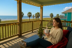 Eine Person sitzt auf einer Veranda mit Blick auf das Meer und hält eine Tasse.